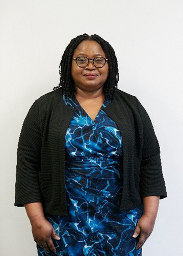 Benedicta Agbagwara-Osuji, a Black woman with glasses and long black hair, wearing a black jacket over a blue dress